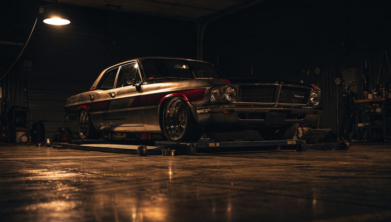 A classic car on the lift in the Car Nuts bay at night